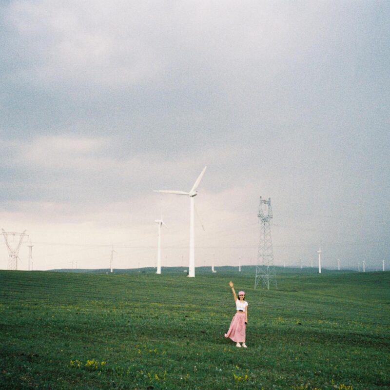 A woman stands in a field of wind turbines in Inner Mongolia, China, capturing the essence of renewable energy.