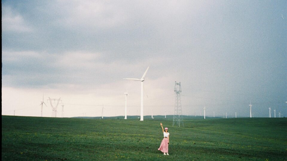 A woman stands in a field of wind turbines in Inner Mongolia, China, capturing the essence of renewable energy.
