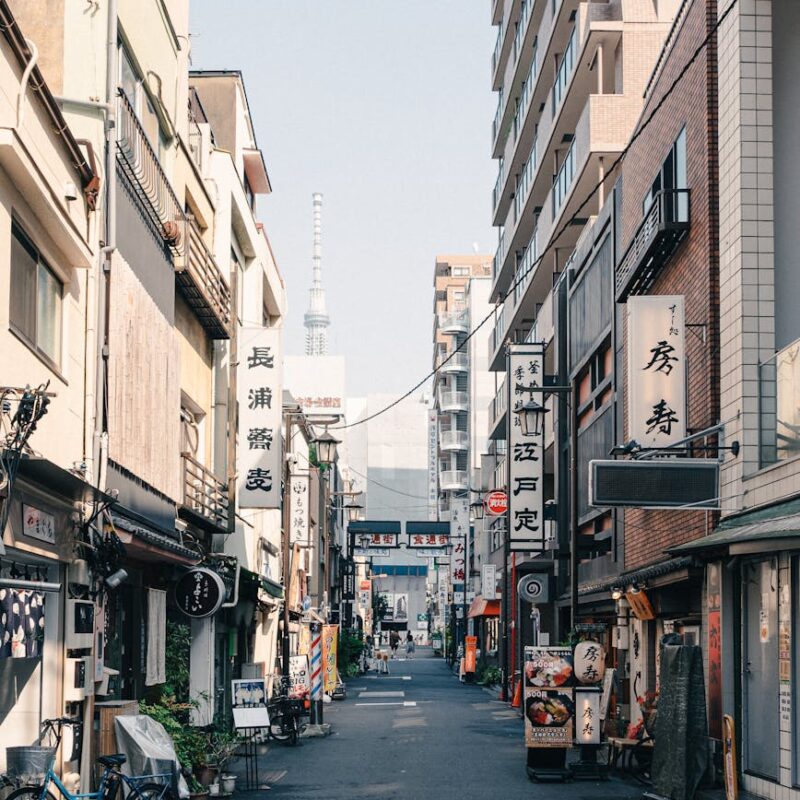A lively street in Tokyo with signs, bikes, and a view of Tokyo Skytree in the distance.
