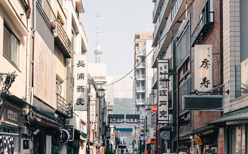 A lively street in Tokyo with signs, bikes, and a view of Tokyo Skytree in the distance.