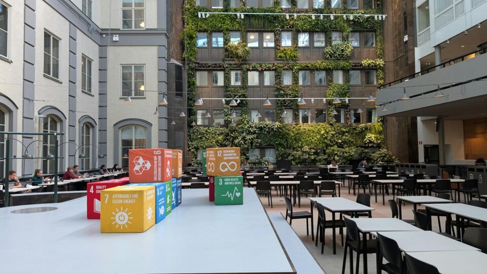 Indoor courtyard with green wall and sustainable development goals displayed on colorful cubes.